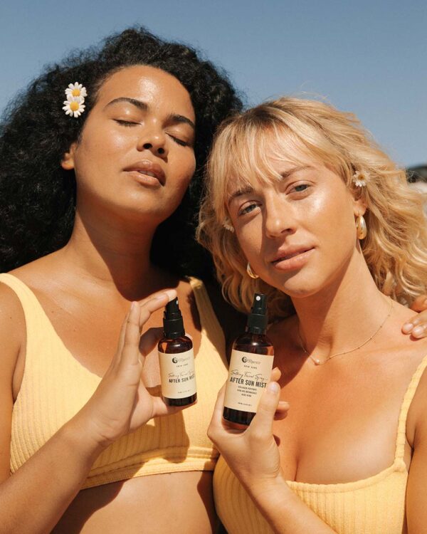 Two women holding bottles of Nutra Organics After Sun Mist Skin Care
