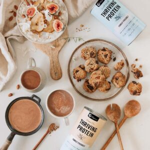 Styled image of Nutra Organics Thriving Protein displayed with drinks, oatmeal, and cookies as ways to use the product