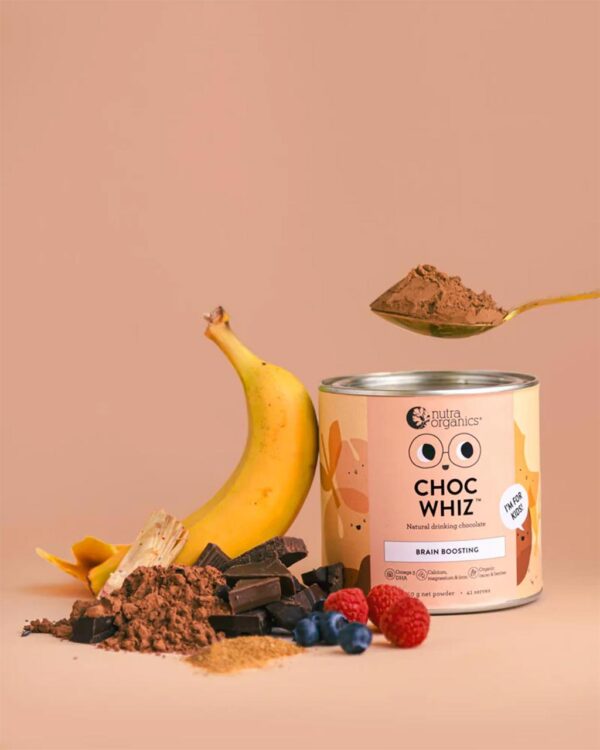 A stylized image of a can of Nutra Organics Choc Whiz natural drinking chocolate for kids placed beside an arrangement of a banana, raspberries, blueberries, chocolate powder, and chocolate pieces